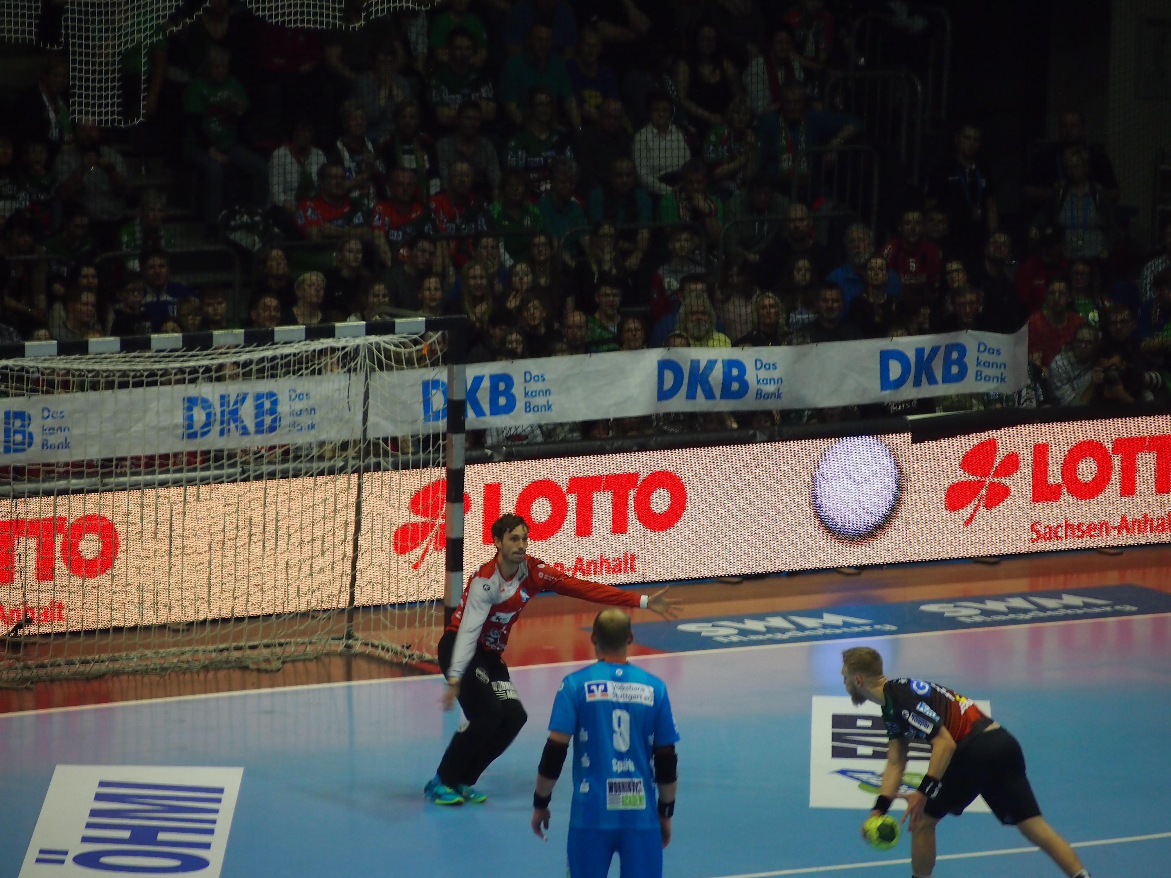 Drei Spieler eines Handballspiels bewegen sich vor dem Tor mit einem Ball