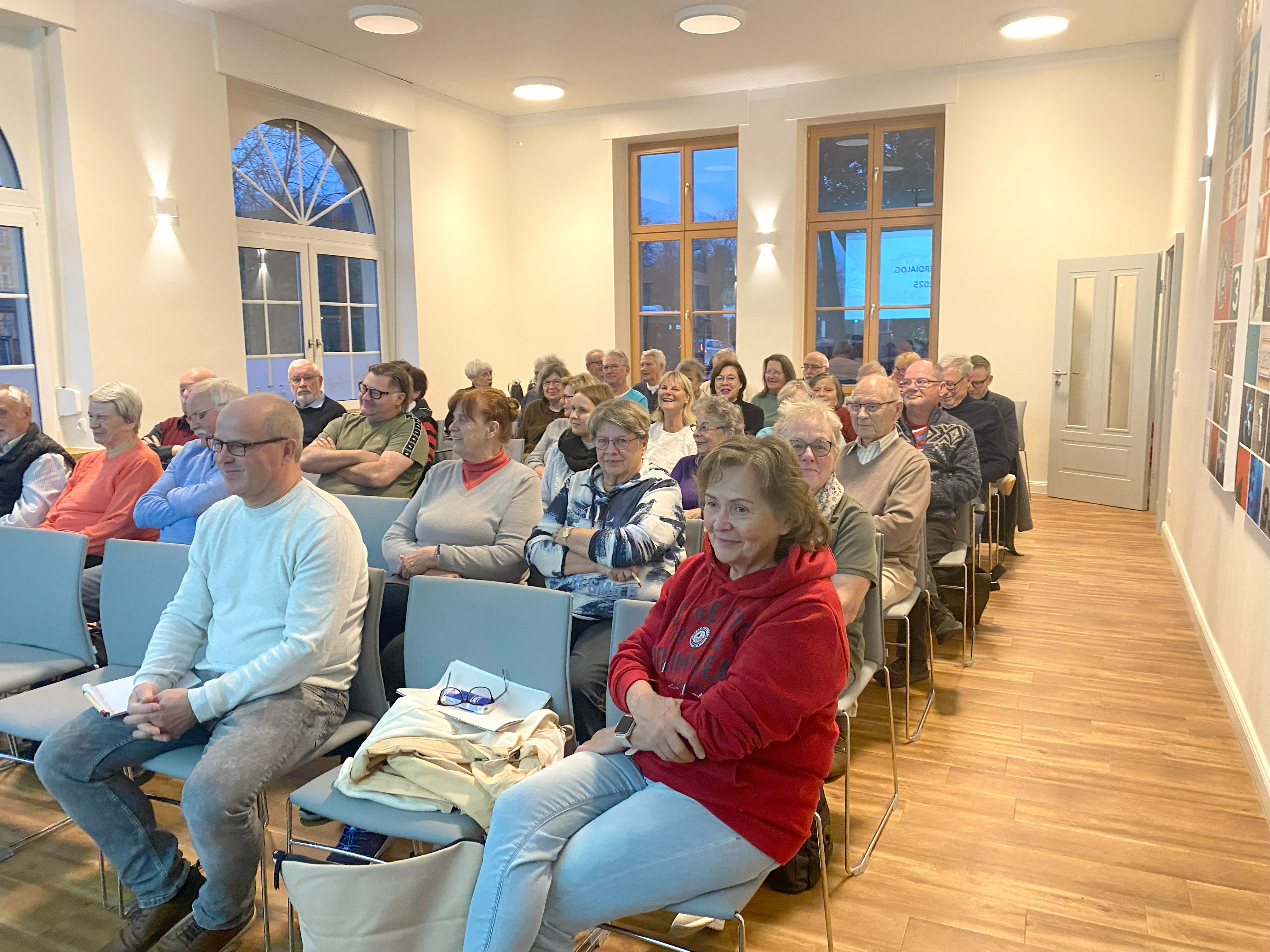 Mieter und Mitglieder sitzen auf Stuhlreihen im Veranstaltungsraum des 1893-Treff