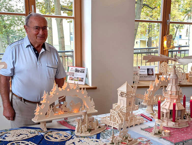 Herr Niemann präsentiert seine handgefertigten Schwibbögen und filigranen Holzkunstwerke bei der Ausstellung im 1893-Treff.