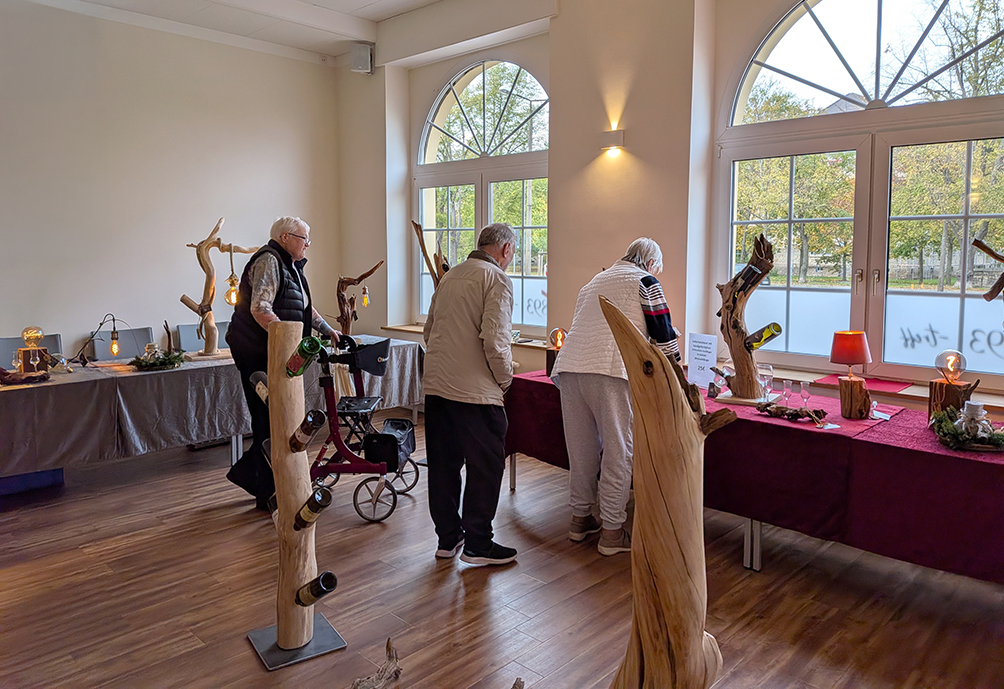 Besucher betrachten handgefertigte Holzkunstwerke und Leuchten bei der Ausstellung im 1893-Treff.