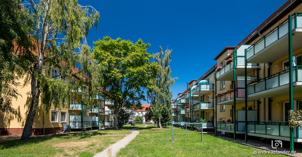 Hinterhof im Grünen mit Häuserreihen auf beiden Seiten mit Balkonen